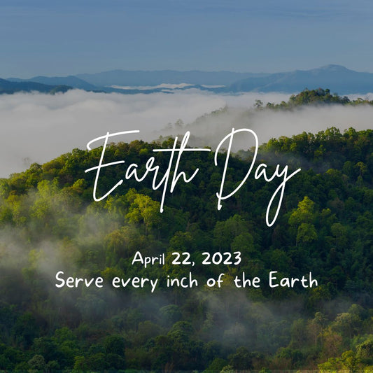 A picture of a view from the top of a mountain. In the proximity, you can see a forest, which slowly drifts into the clouds. The message displayed on top of the picture says " Earth Day April 22,2023, Serve every inch of the Earth"